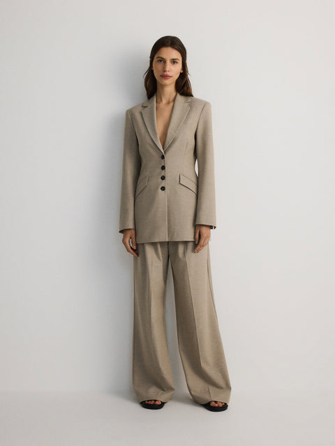 Woman wearing a beige suit on a plain background
