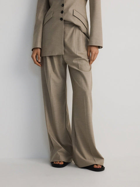 Person wearing a beige suit against a white background
