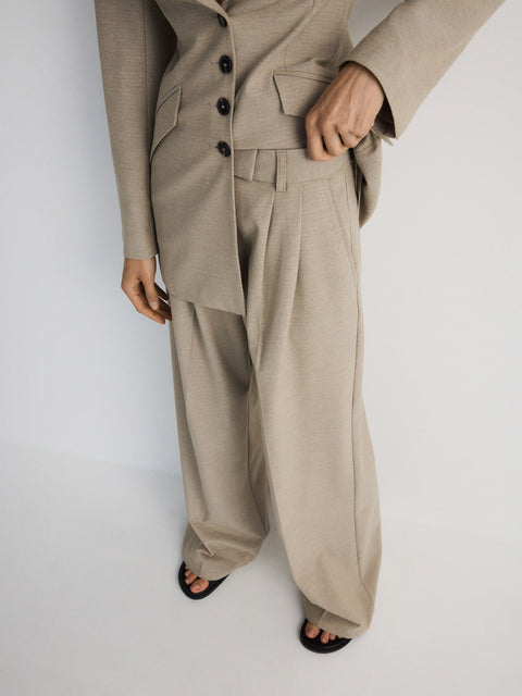 Person wearing a beige suit with wide-leg pants on a white background