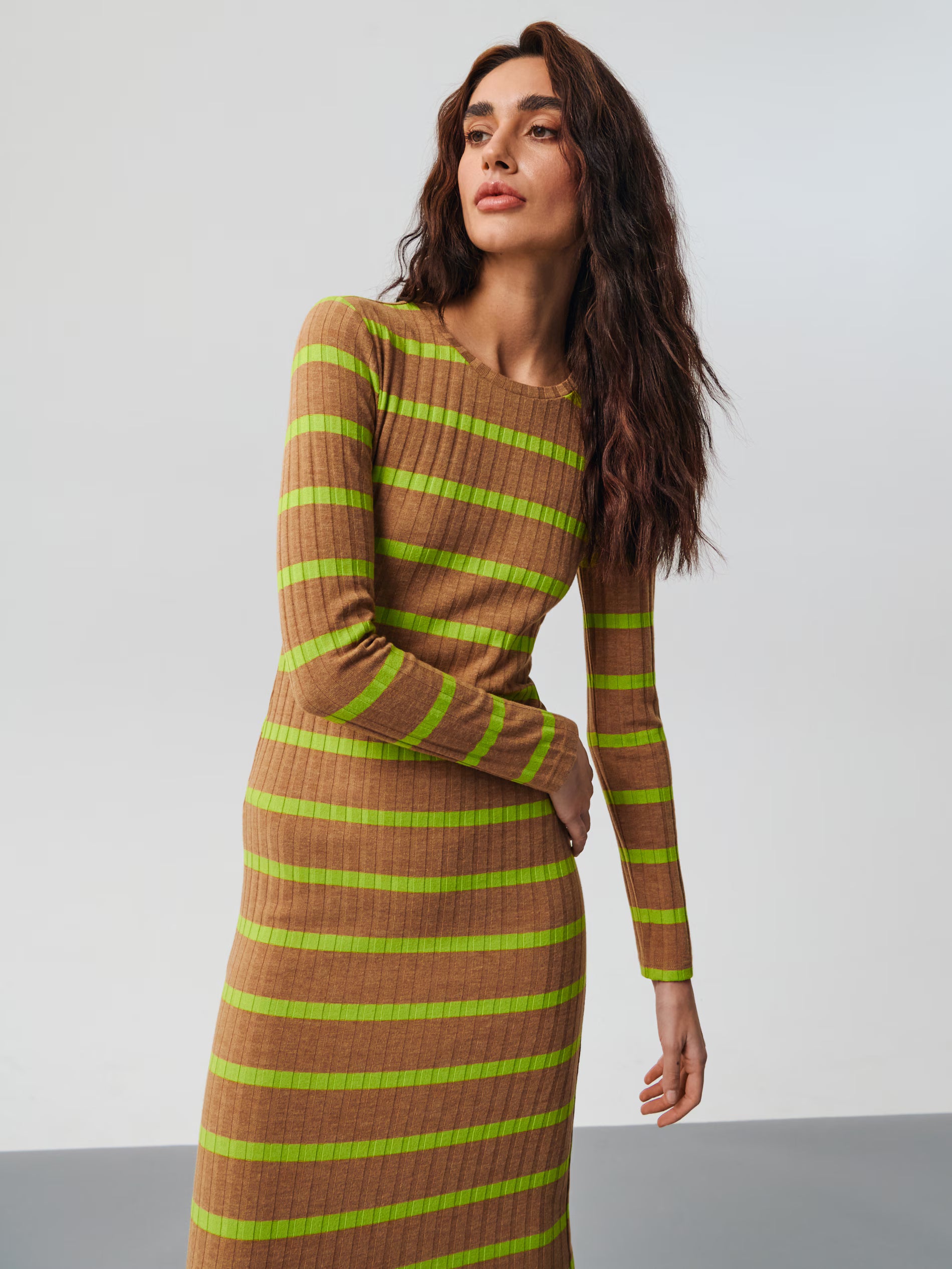Woman wearing a brown and green striped dress against a white background
