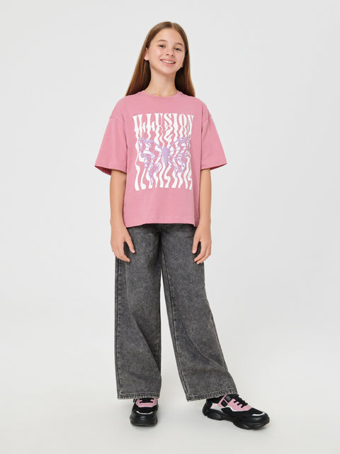 Person wearing a pink t-shirt with a graphic design and gray pants on a white background