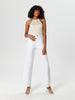 Woman wearing a cream top and white pants on a white background