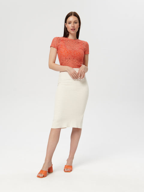 Woman wearing an orange top and white skirt on a white background