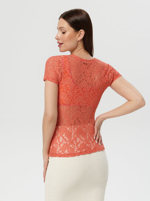 Woman wearing a coral lace top against a white background