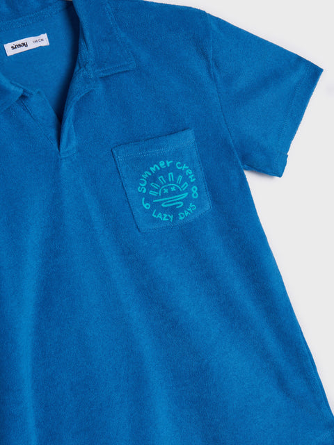 Blue t-shirt with a logo on the chest pocket against a white background