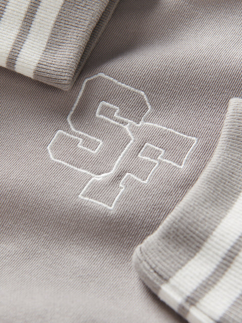 Close-up of a gray fabric with an embroidered logo, possibly a brand emblem.