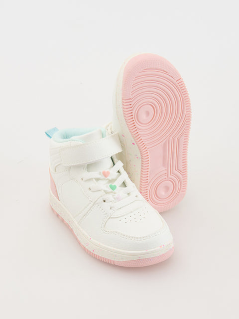 White high-top sneakers with pink soles on a light gray background
