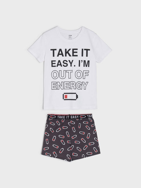 A boy's white short-sleeve pajama set with text graphic on the t-shirt and patterned shorts.