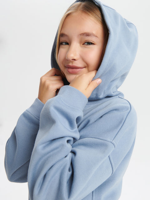 Person wearing a light blue hoodie on a plain background
