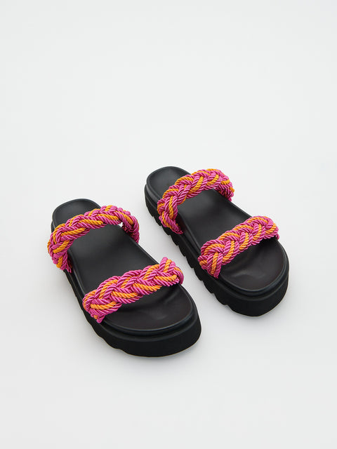 Black sandals with pink and yellow braided straps on a white background