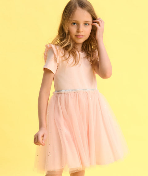 Young girl wearing a light pink dress against a yellow background