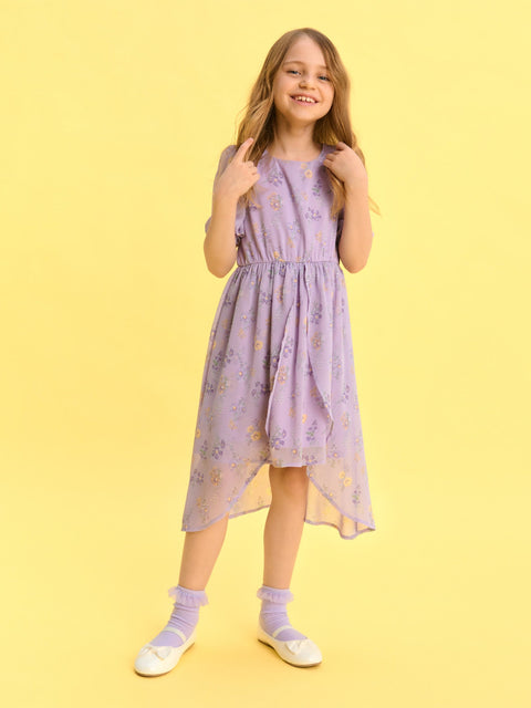 Young girl wearing a light purple dress with floral pattern on a yellow background