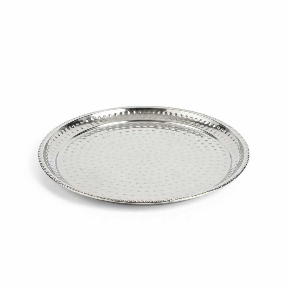 Round metal tray with textured surface on a wooden floor