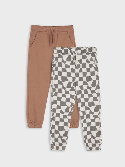 Two pairs of jogger pants, one brown and one with a geometric pattern, on a white background.
