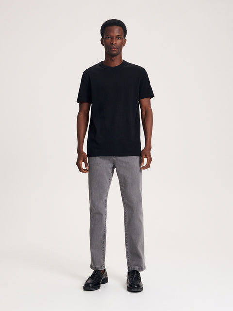 Person wearing a black t-shirt and gray jeans on a white background