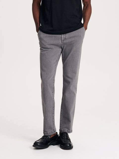 Person wearing gray pants and black shoes on a white background