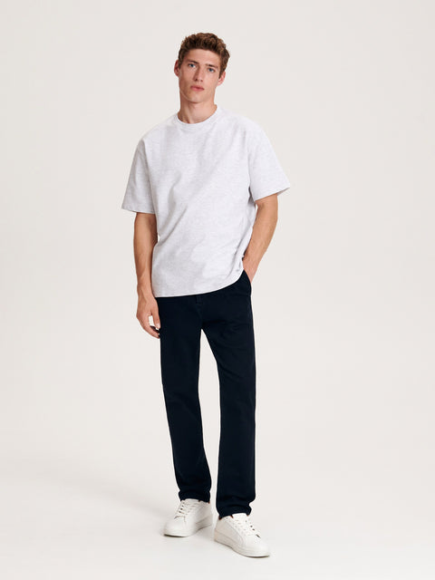 Person wearing a white t-shirt and dark pants on a white background