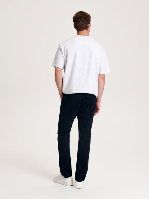 Person wearing a white t-shirt and dark pants on a plain background