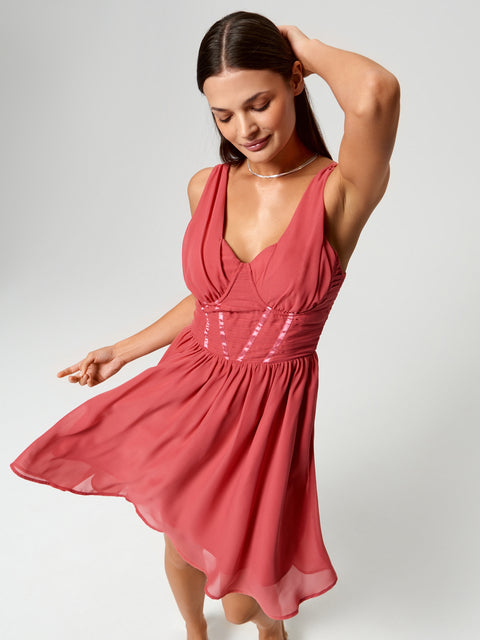 Woman wearing a pink dress with sequin details on a white background