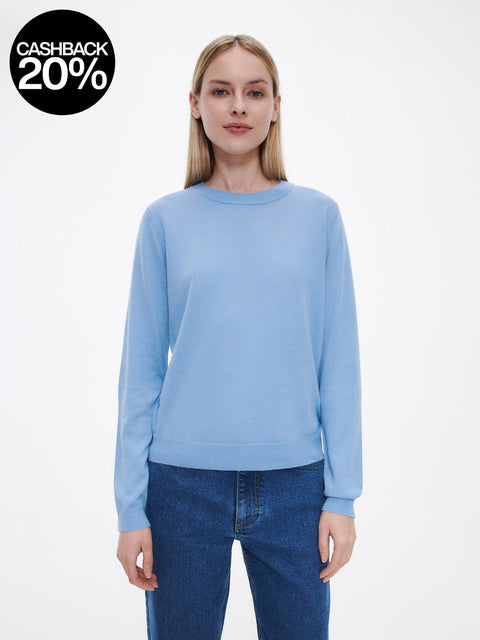 Woman wearing a light blue sweater and jeans on a white background