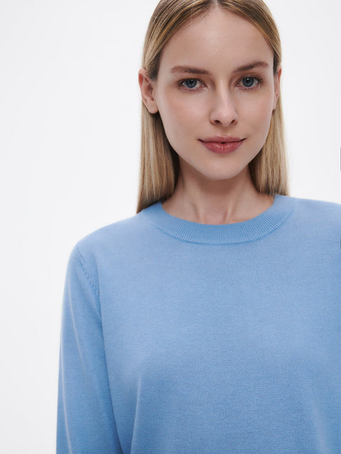 Woman wearing a light blue sweater against a plain background