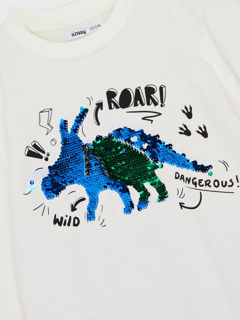 White t-shirt with blue and green sequin dinosaur design and text on a white background