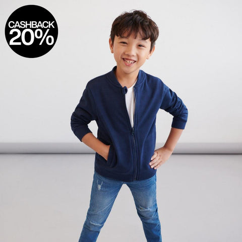 Child wearing a navy blue jacket, white shirt, and jeans on a plain background