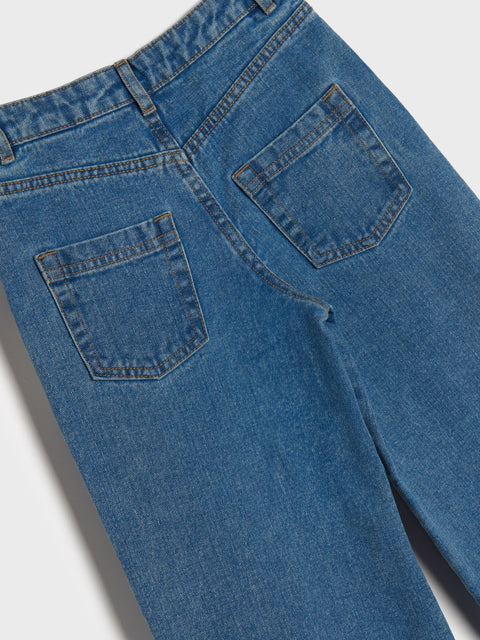 Close-up of blue jeans with a focus on the pockets on a light gray background