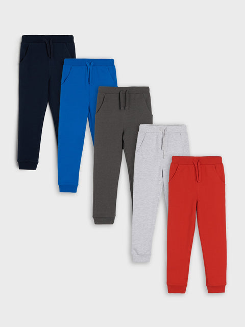 Five pairs of colorful jogger pants on a white background