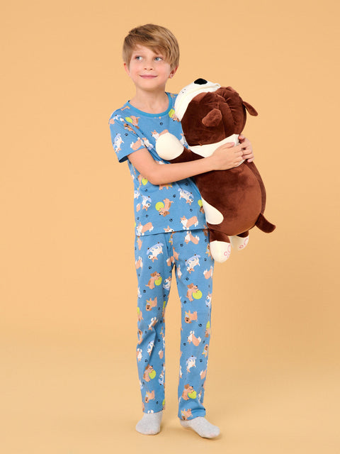 Child wearing blue pajamas with animal patterns, holding a brown plush dog toy against a beige background