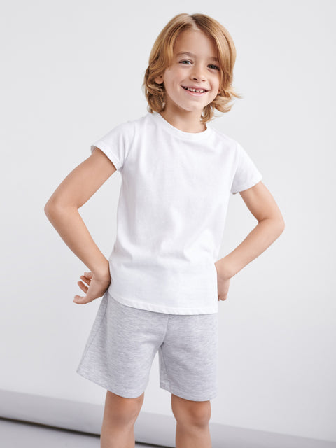 Child wearing a white t-shirt and gray shorts on a white background