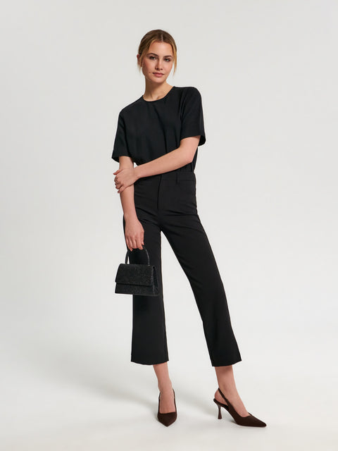 Woman wearing a black outfit with a handbag on a white background