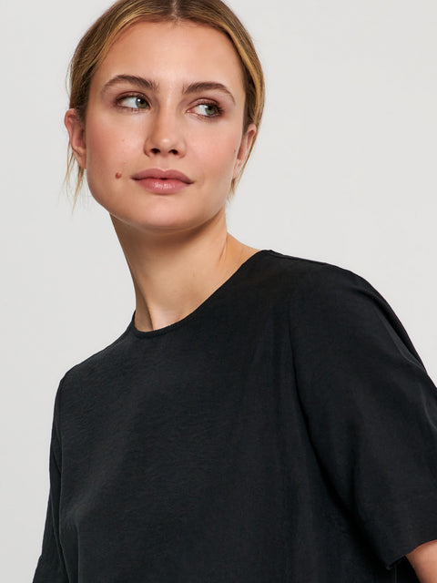 Woman wearing a black t-shirt against a plain background