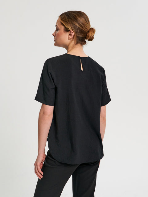 Person wearing a black t-shirt with a cutout design on the back against a light gray background