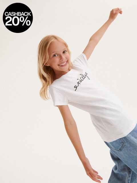 Young girl wearing a white t-shirt with text on a plain background
