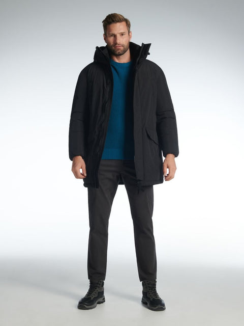 Man wearing a black coat, blue shirt, and black pants on a white background