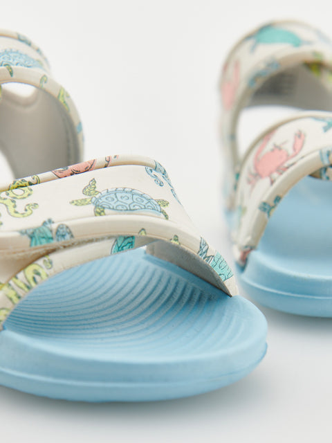 Pair of floral-patterned sandals with blue soles on a light background