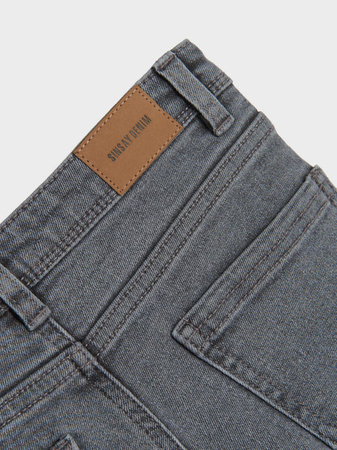 Close-up of gray jeans with a brand label on a light gray background
