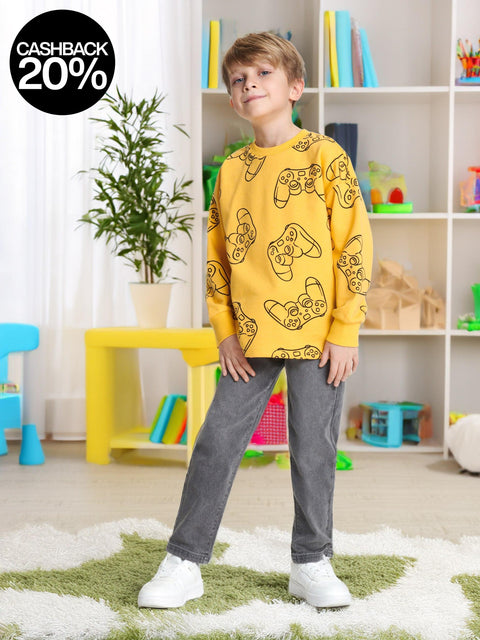 Child wearing a yellow sweatshirt with gaming console graphics in a room with colorful furniture and toys.