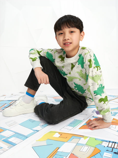 Child sitting on a colorful floor mat wearing a dinosaur-themed shirt.