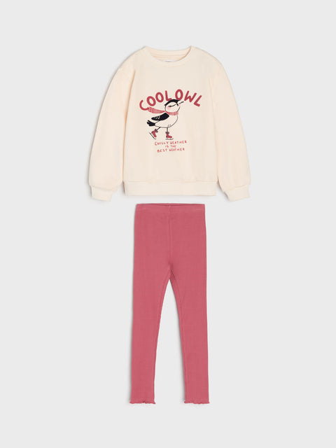 Beige sweatshirt with graphic and text, paired with pink leggings on a light gray background