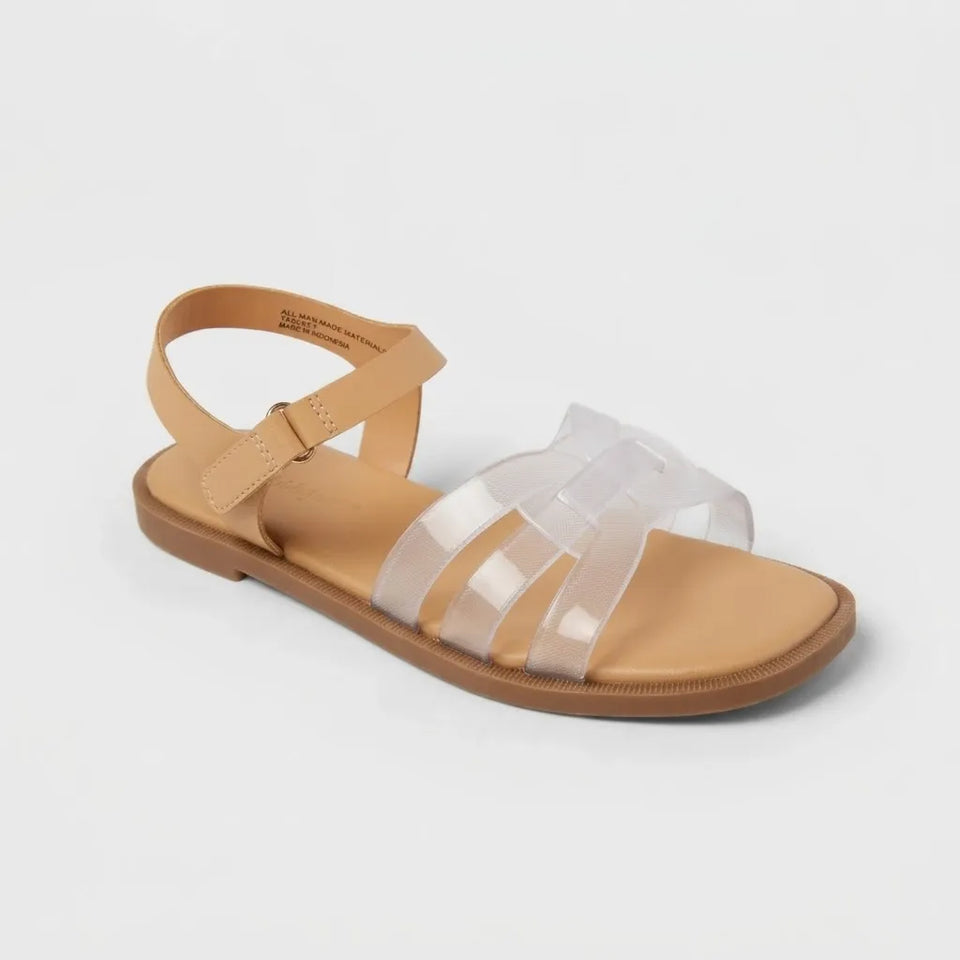 A single flat sandal with a tan footbed and sole, featuring clear transparent crisscross straps on a light gray background.