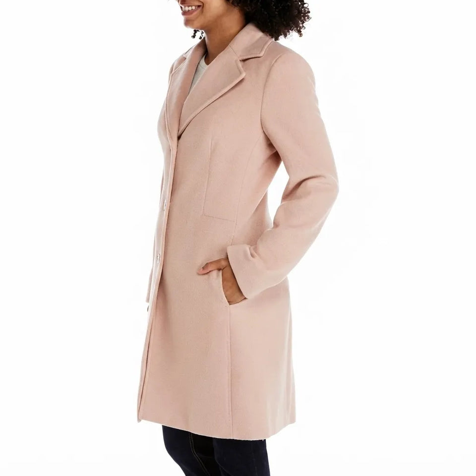 A woman wearing a light blush pink mid-length coat with notch lapels and front patch pockets, shown in a side profile against a plain white background.
