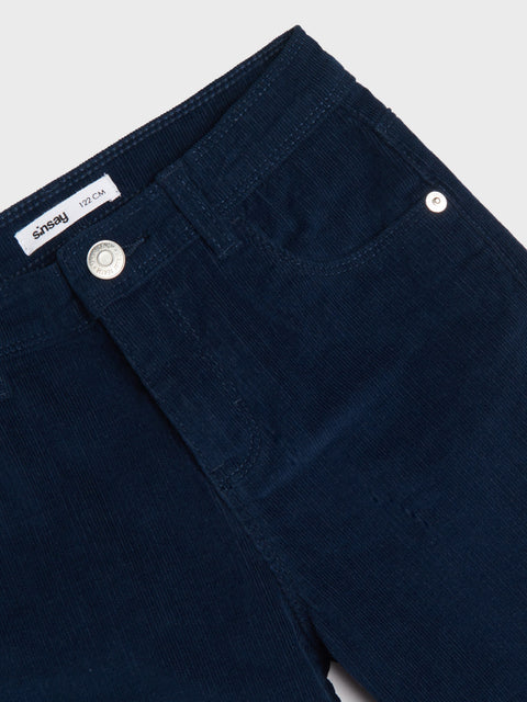 Close-up of dark blue pants with a brand label on a light gray background