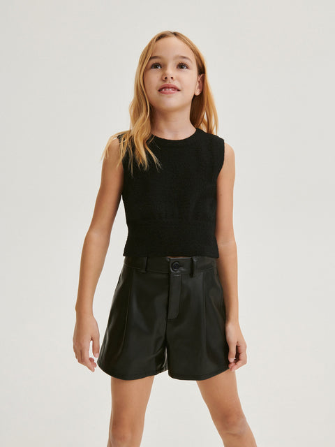 Young girl wearing a black sleeveless top and black shorts on a white background