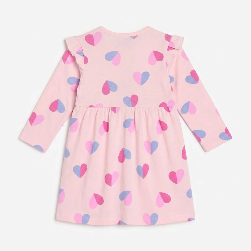 A pink long-sleeve baby dress with a ruffled neckline and a scattered heart pattern in pink, purple, and blue, shown against a plain light background.