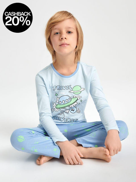 Child wearing a light blue pajama set with an alien design on a white background