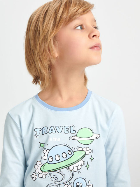 Child wearing a light blue pajama top with space-themed design and 'Travel' text.