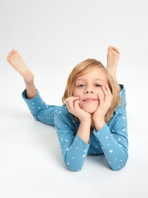 Child wearing blue pajamas with white stars, lying on a white background