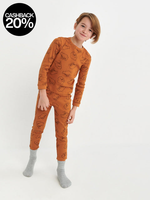 Child wearing a rust-colored pajama set with a pattern on a white background